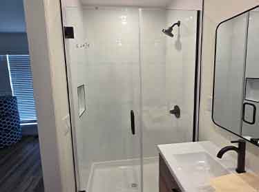 Custom glass shower enclosure with sliding door in a New York City home bathroom.